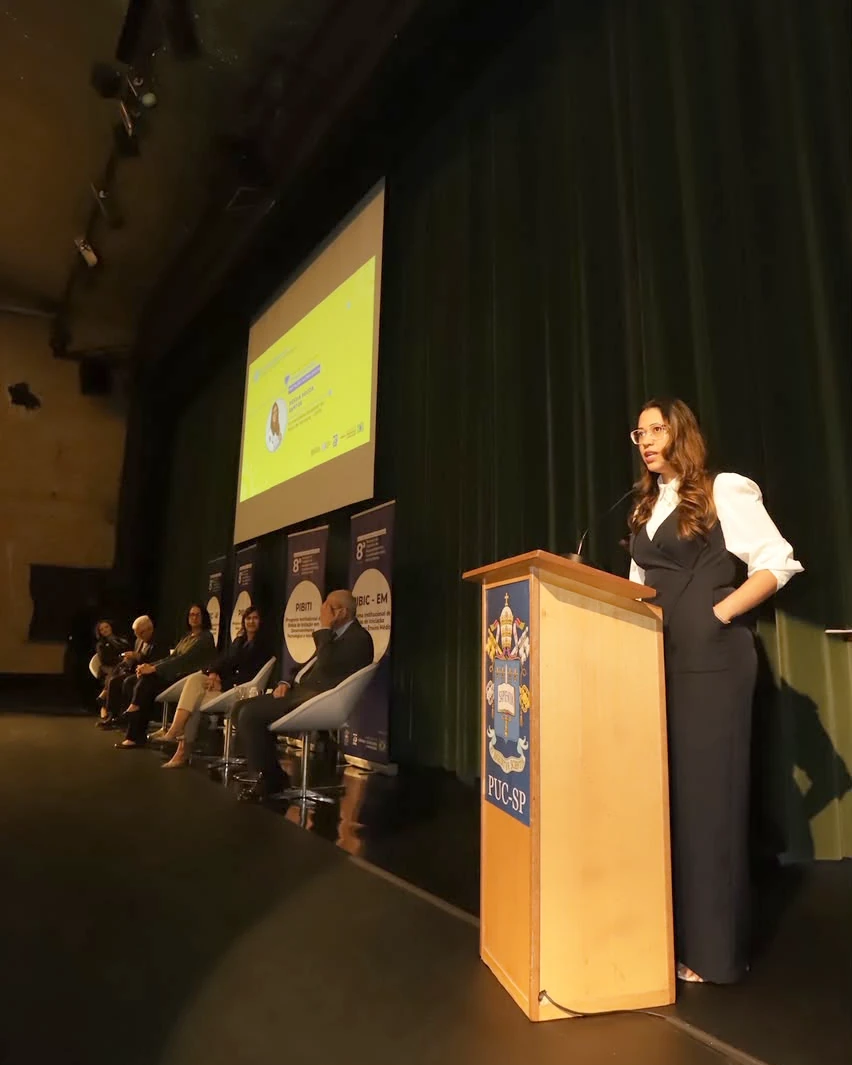 Késsia Souza Santos giving a speech at the PUC-SP lectern during the award ceremony